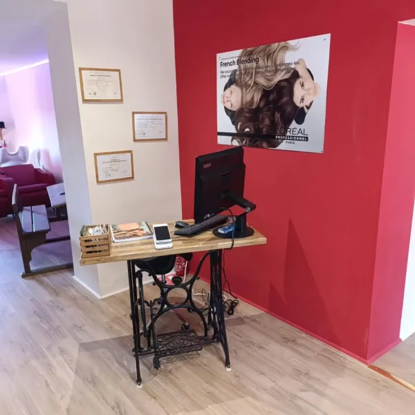 Comptoir d’accueil du salon posé sur une machine à coudre ancienne, diplômes au mur