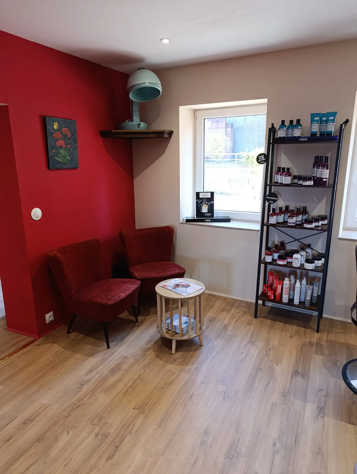 Le coin d’attente du salon La Boucle Rouge, fauteuils rouges et produits professionnels